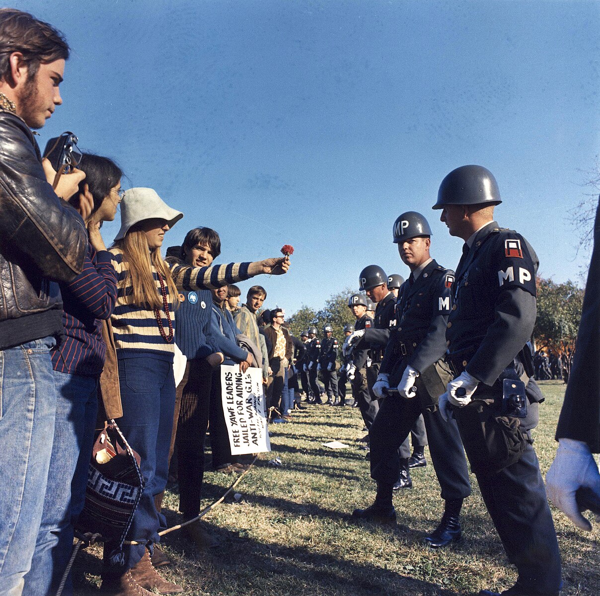 Outside the Pentagon, 1967. A line of youth protesting the Vietnam War stand before a line of military police. A protester offers a flower to a military policeman. 